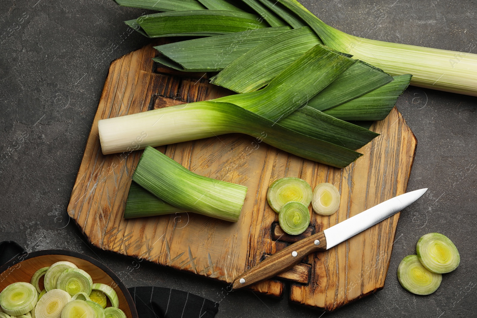 Photo of Flat lay composition with fresh raw leek on dark grey table. Ripe onion