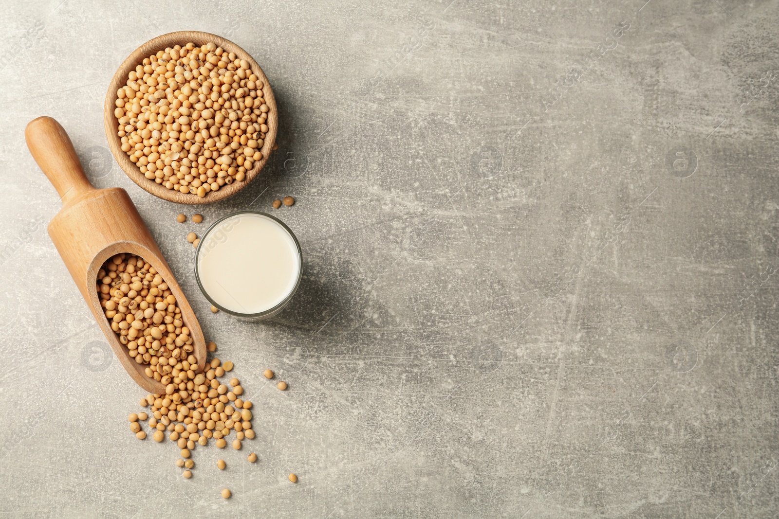 Photo of Glass with fresh soy milk and grains on grey table, flat lay. Space for text