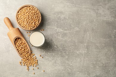 Glass with fresh soy milk and grains on grey table, flat lay. Space for text