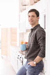 Photo of Portrait of confident young man with cup in kitchen