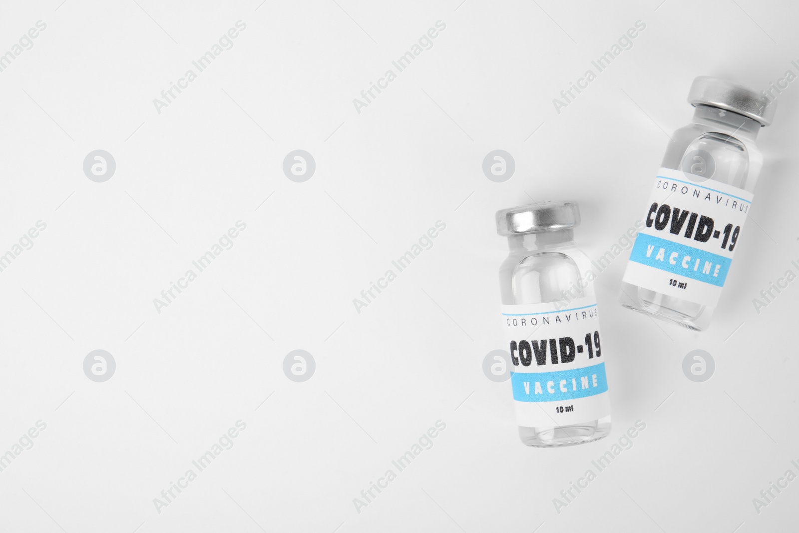 Photo of Vials with coronavirus vaccine on white background, flat lay. Space for text