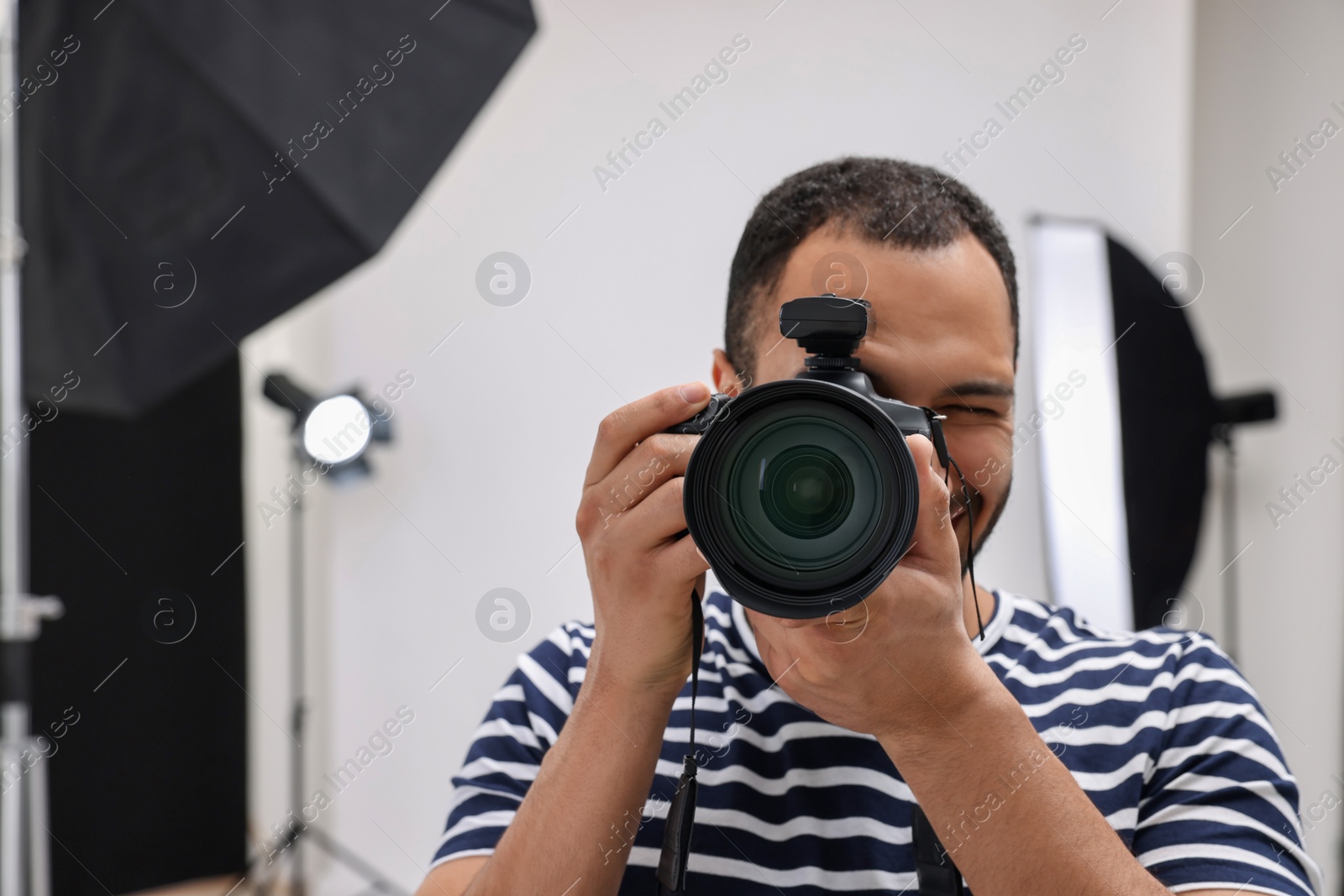 Photo of Professional photographer taking picture in modern photo studio, space for text