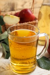 Photo of Delicious apple cider in glass mug on white wooden table