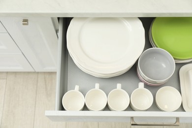 Clean plates, bowls and cups in drawer indoors, top view