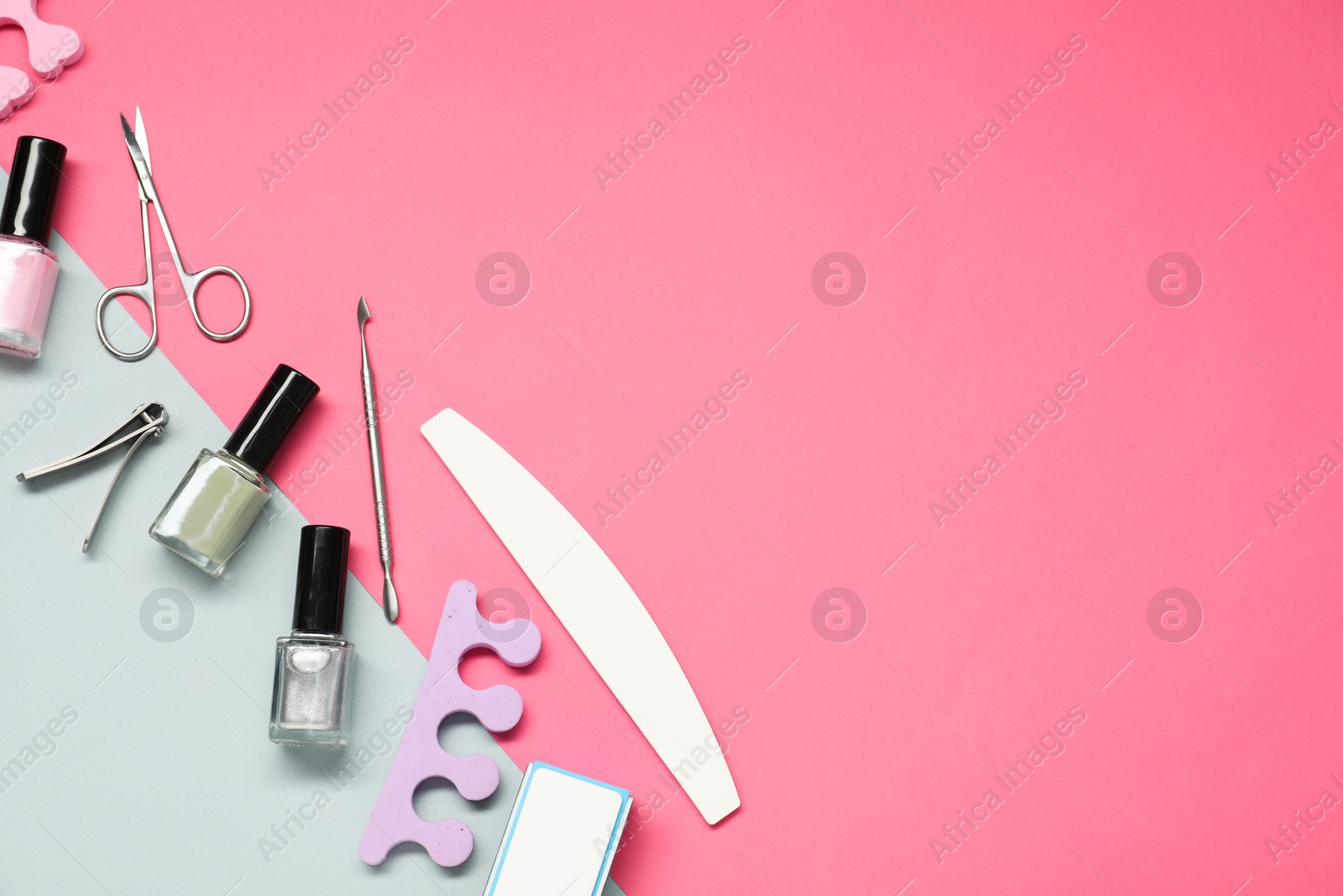 Photo of Nail polishes and set of pedicure tools on color background, flat lay. Space for text