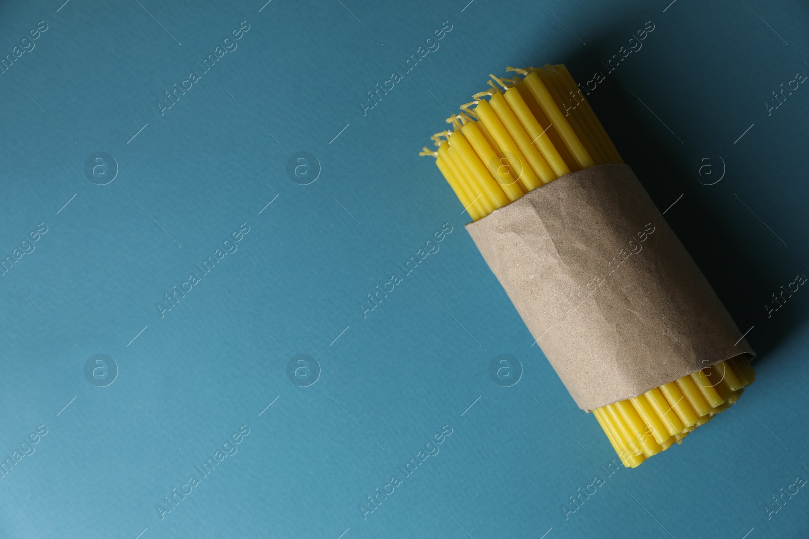 Photo of Many church wax candles on light blue background, top view. Space for text