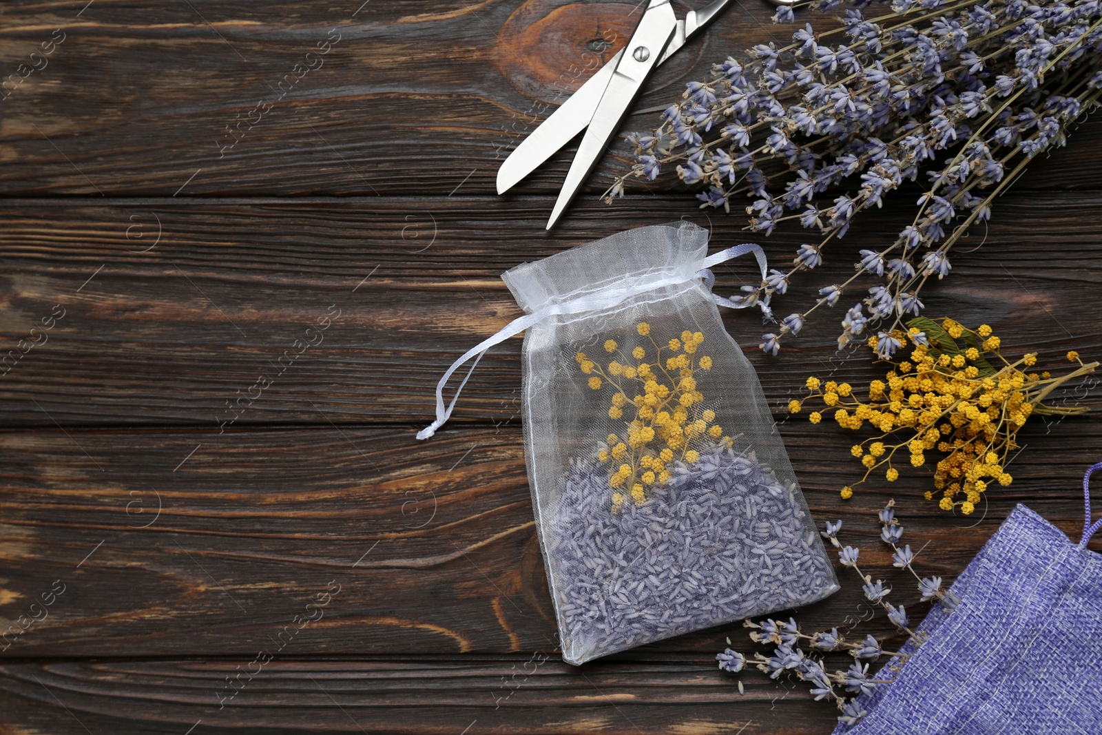 Photo of Scented sachet with mixed dried flowers and scissors on wooden table, flat lay. Space for text