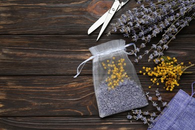 Scented sachet with mixed dried flowers and scissors on wooden table, flat lay. Space for text