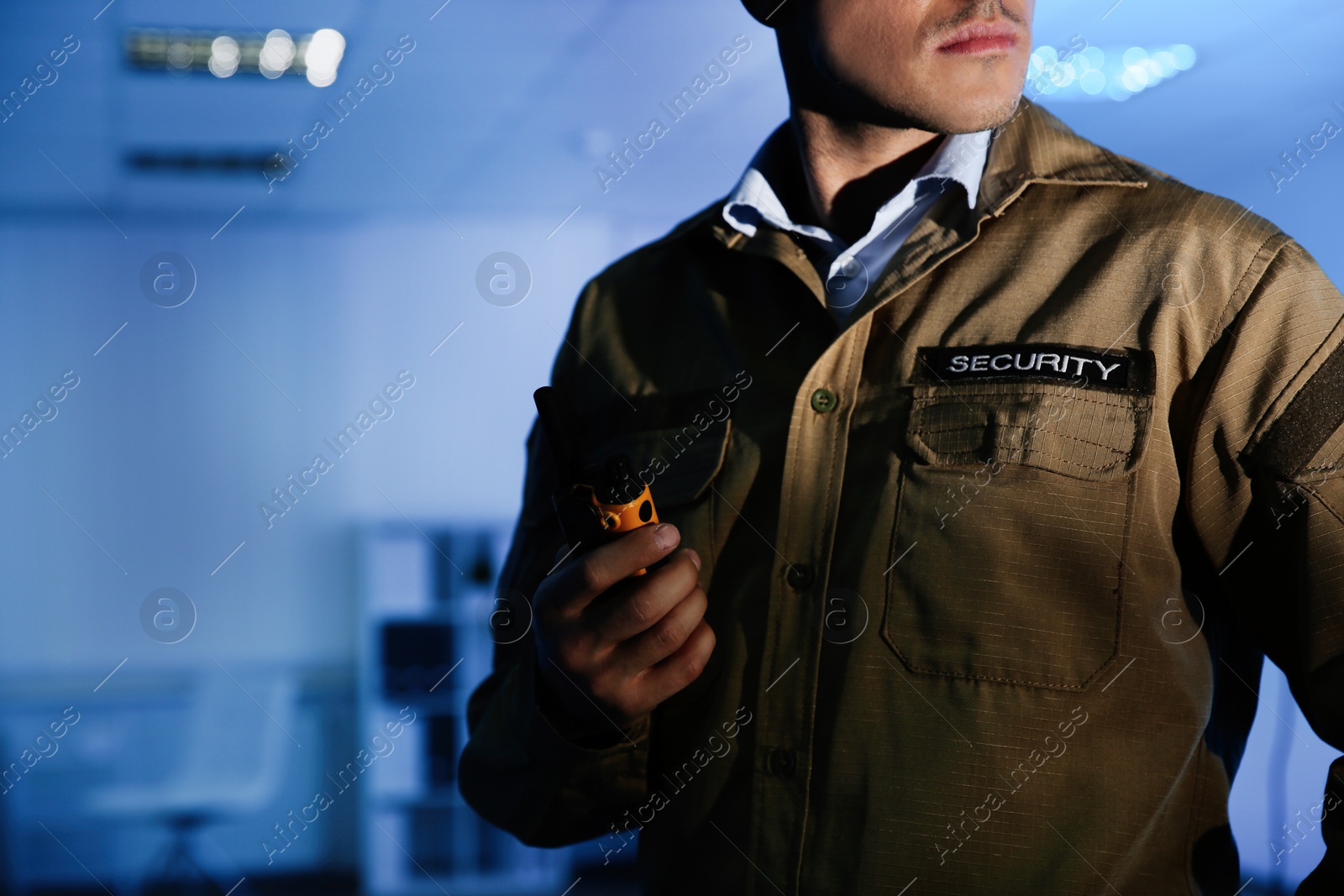 Photo of Professional security guard with portable radio set in dark room, closeup