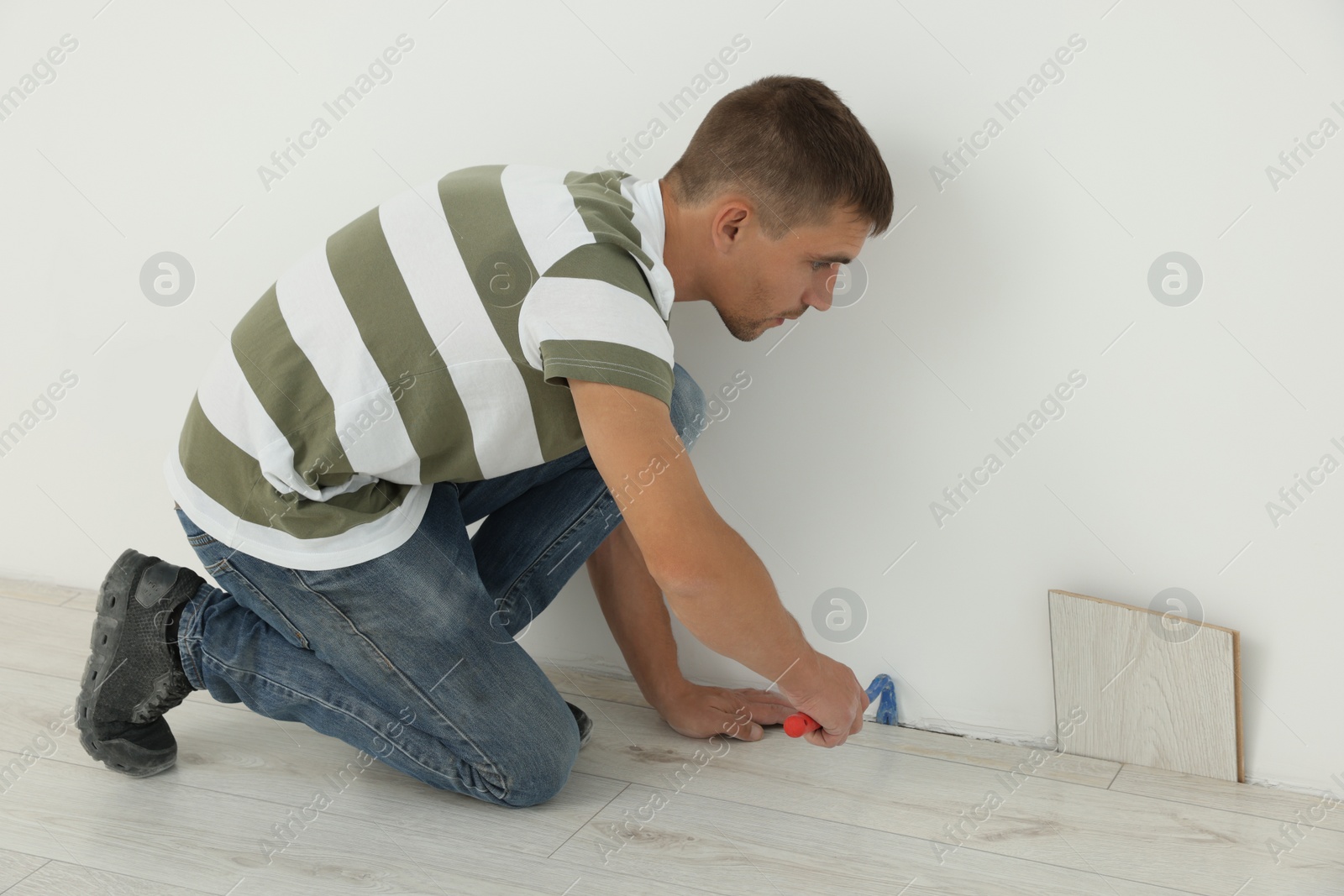 Photo of Professional worker using nail puller during installation of new laminate flooring indoors