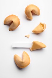 Many tasty fortune cookies with predictions on white background, flat lay. Space for text
