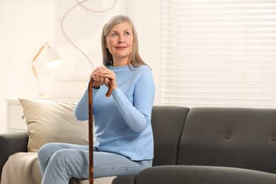 Photo of Mature woman with walking cane on sofa at home