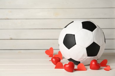 Photo of Soccer ball and hearts on white wooden table. Space for text