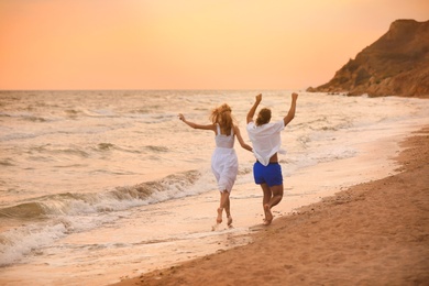 Photo of Young couple having fun on beach at sunset