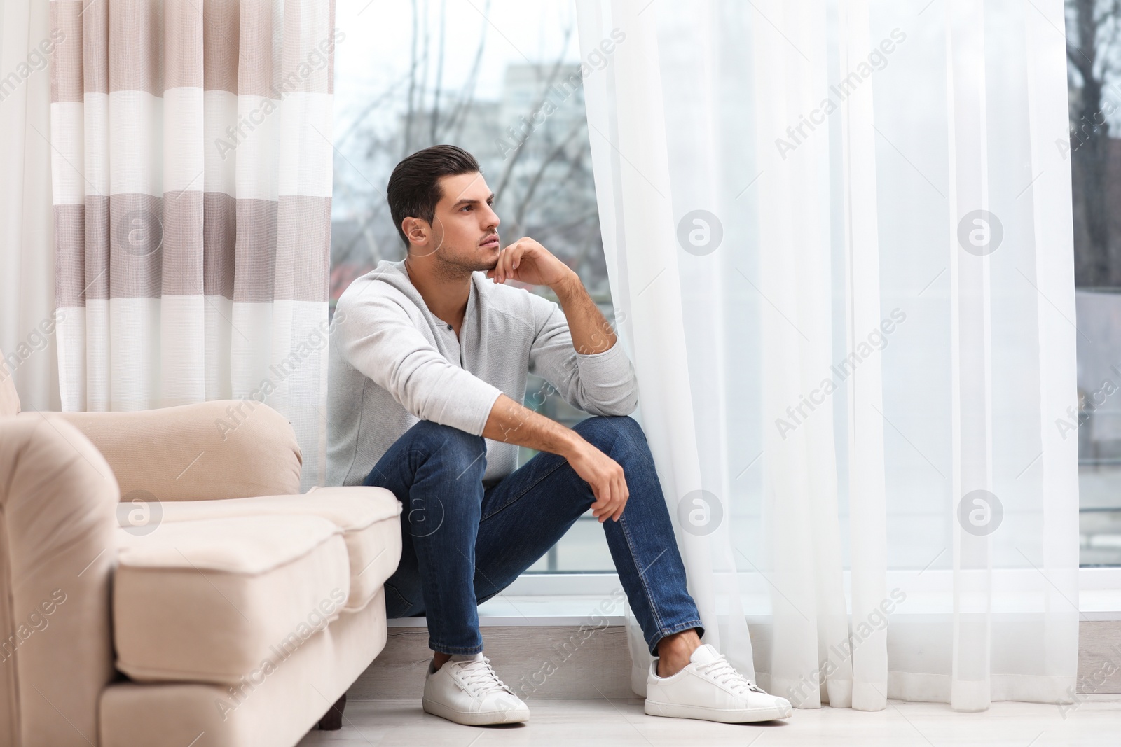 Photo of Handsome man resting near window at home