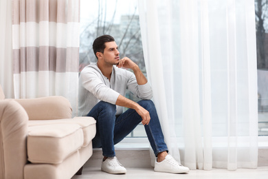 Handsome man resting near window at home