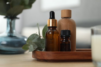 Photo of Aromatherapy. Bottles of essential oil and eucalyptus leaves on wooden table