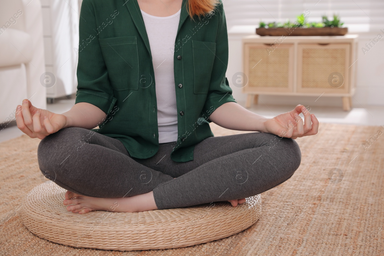 Photo of Woman meditating on wicker mat at home, closeup