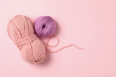 Photo of Soft woolen yarns on pink background, flat lay. Space for text