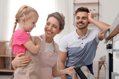 Photo of Happy family baking food in oven at home