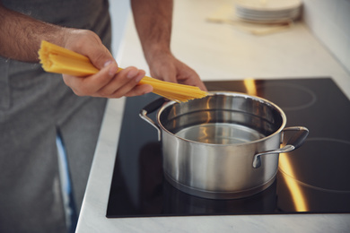 Man cooking pasta on stove in kitchen, closeup