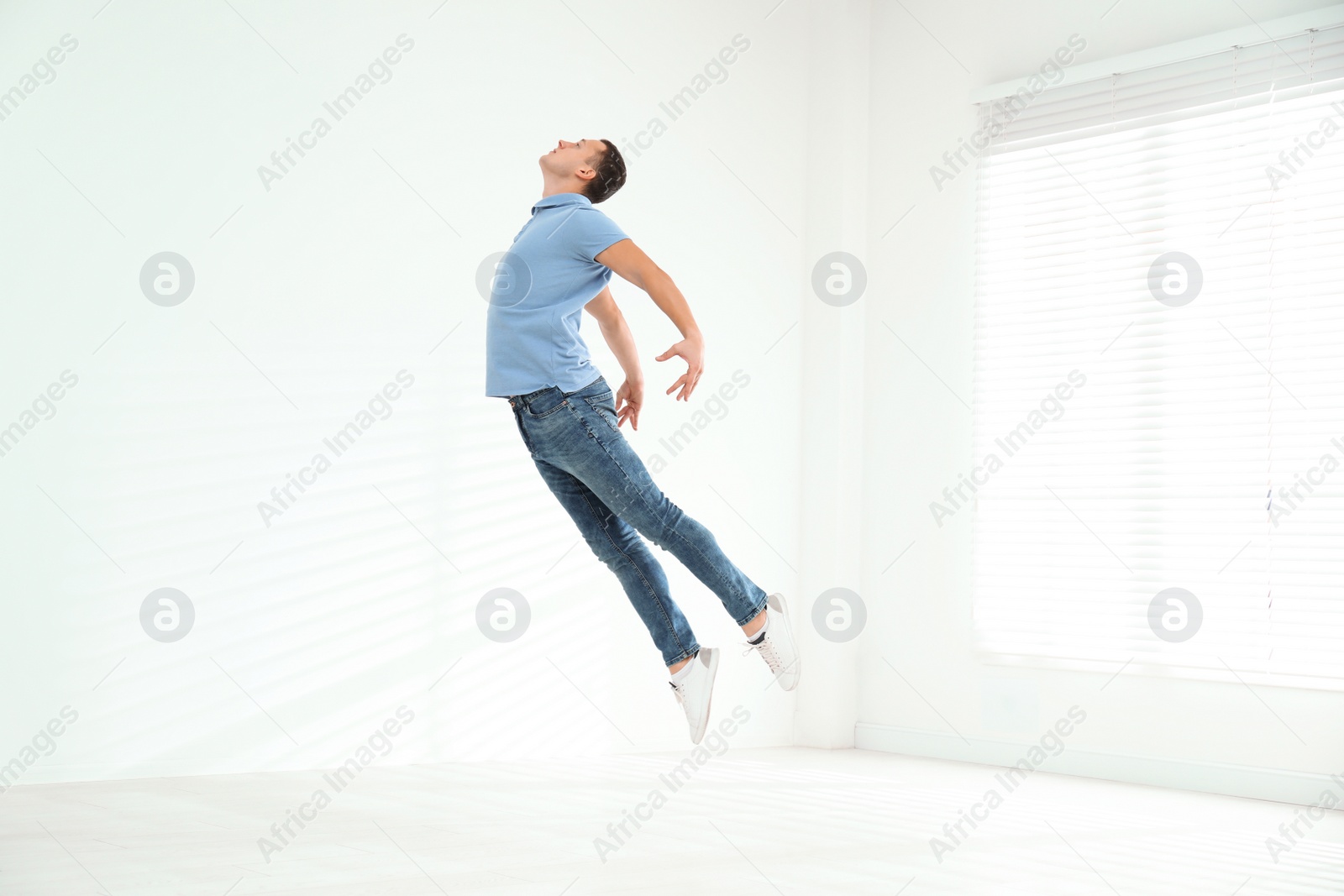 Photo of Handsome young man jumping indoors. Modern dance