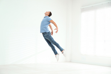 Photo of Handsome young man jumping indoors. Modern dance