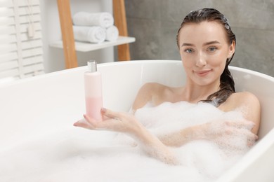 Photo of Woman taking bath with shower gel in bathroom