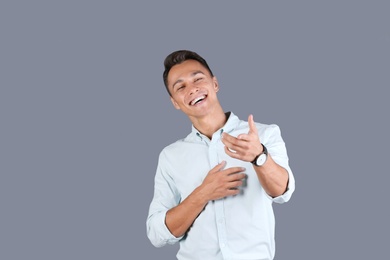 Photo of Portrait of handsome young man laughing on color background