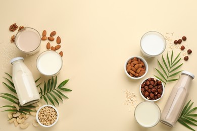 Different vegan milks and ingredients on beige background, flat lay. Space for text