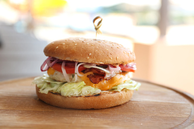 Photo of Delicious fresh burger with bacon on wooden board