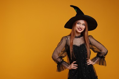 Photo of Happy young woman in scary witch costume on orange background, space for text. Halloween celebration