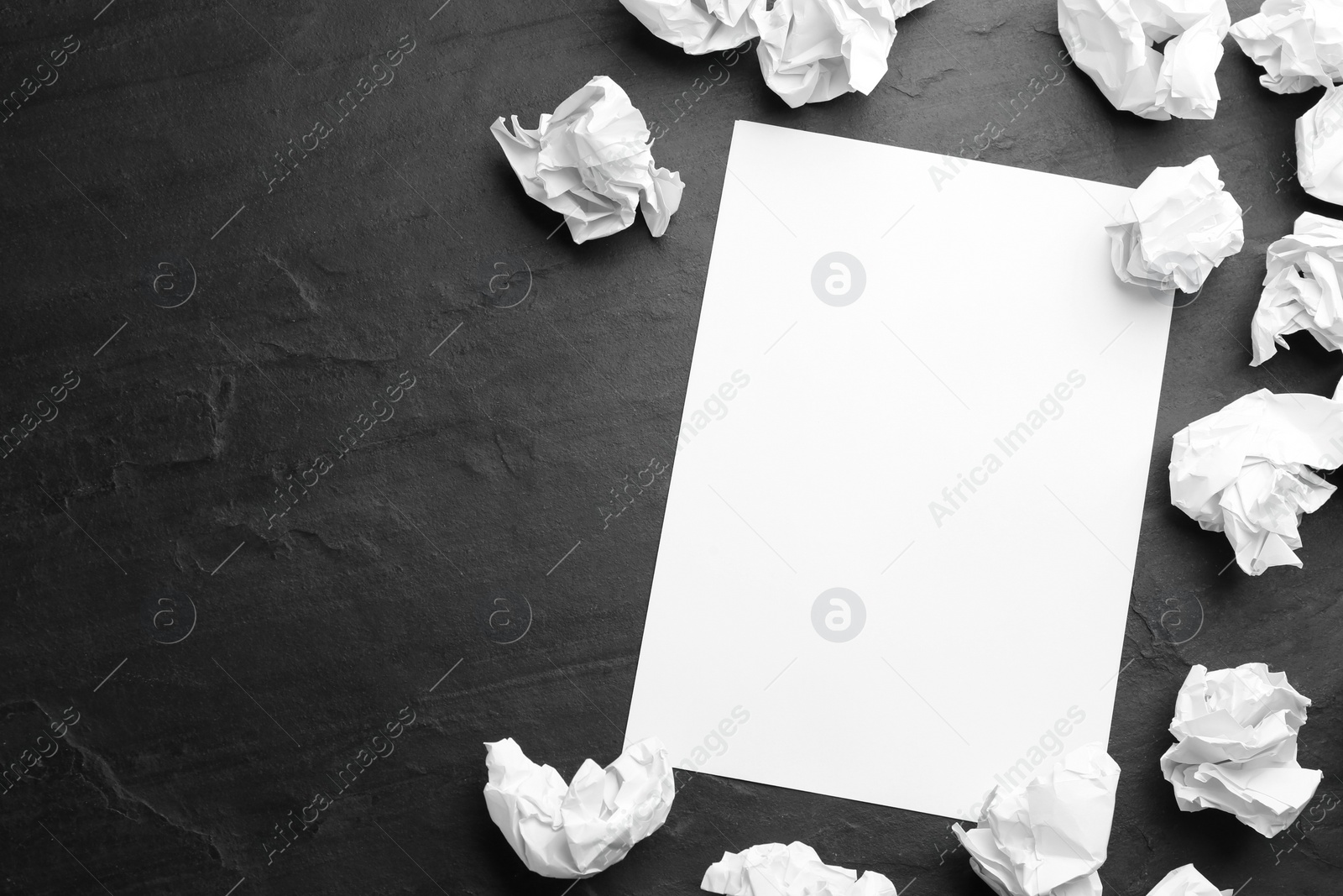 Photo of Blank sheet and crumpled paper balls on black background, flat lay. Space for text