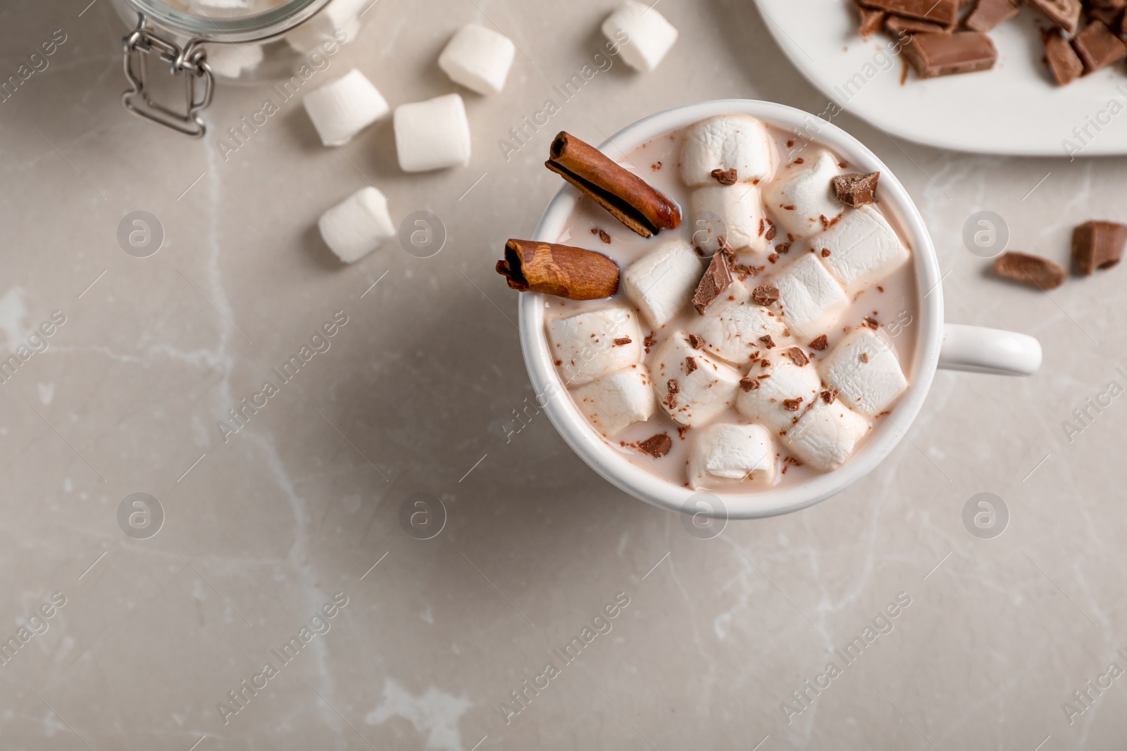Photo of Tasty hot chocolate with milk and marshmallows in cup on table, top view. Space for text