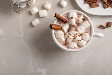 Photo of Tasty hot chocolate with milk and marshmallows in cup on table, top view. Space for text