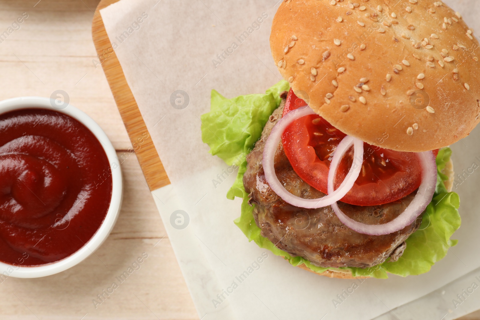 Photo of Tasty hamburger with patty and vegetables served on light wooden table, flat lay