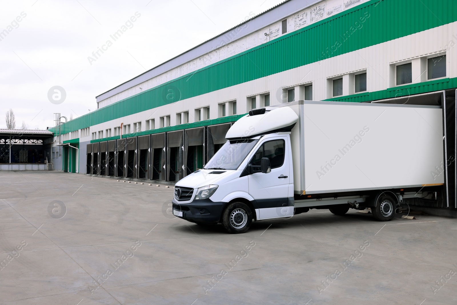 Image of Truck near loading dock of warehouse outdoors. Logistics center