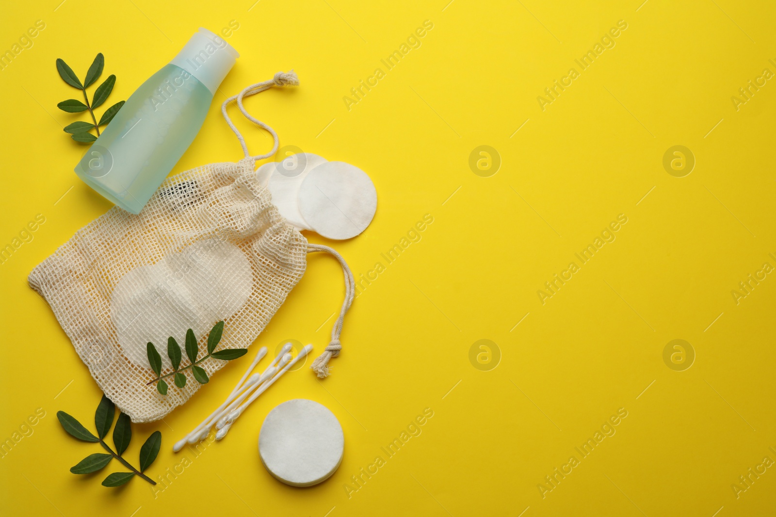 Photo of Cotton pads, swabs and makeup removal product on yellow background, flat lay. Space for text