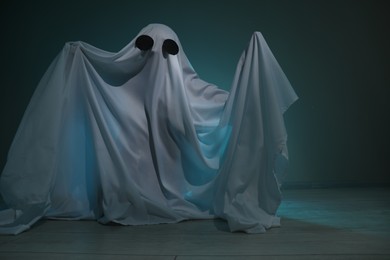 Creepy ghost. Woman covered with sheet on dark teal background