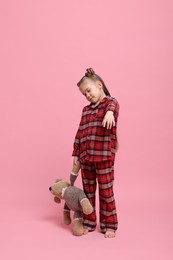 Photo of Girl in pajamas with toy bear sleepwalking on pink background