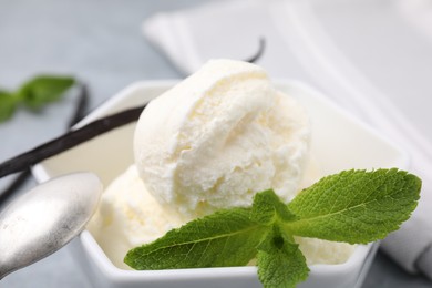Photo of Delicious vanilla ice cream with mint in bowl, closeup
