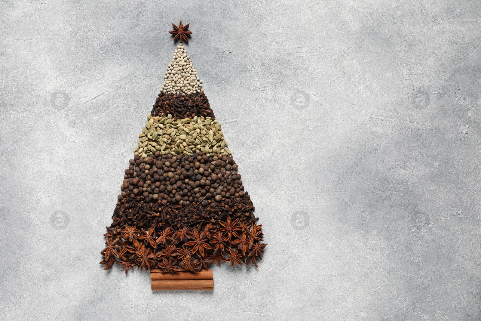 Photo of Christmas tree made of different spices on gray textured table, top view. Space for text