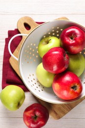 Photo of Fresh apples in colander on white wooden table, flat lay