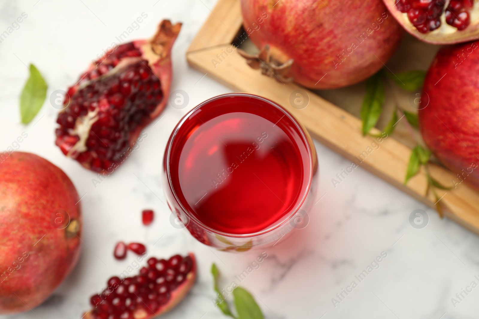 Photo of Tasty pomegranate juice in glass and fresh fruits on white marble table, flat lay