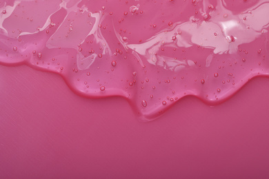 Photo of Pure transparent cosmetic gel on pink background, top view