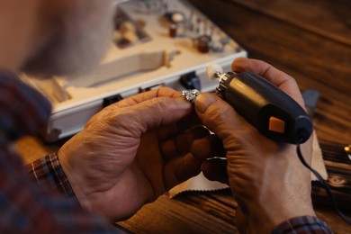 Photo of Professional jeweler working with gemstones at wooden table, closeup