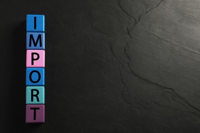 Photo of Word Import made of color cubes on black background, top view, Space for text