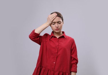 Woman suffering from headache on light grey background. Cold symptoms