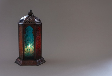 Photo of Muslim lamp with candle on gray background. Fanous as Ramadan symbol