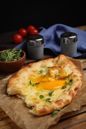 Photo of Delicious Adjarian khachapuri with cheese and egg on wooden table
